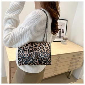 Detail of leopard print handbag featuring metal rivet lock and dark gunmetal chain strap