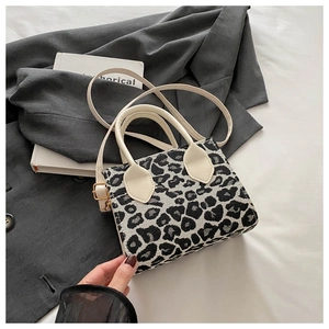 Detail of leopard print woven bag with white leather handle and metal strap buckle