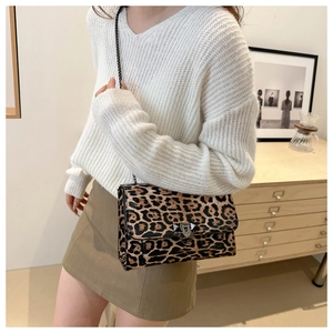 Close-up of leopard print flap bag with black chain strap worn by a female model