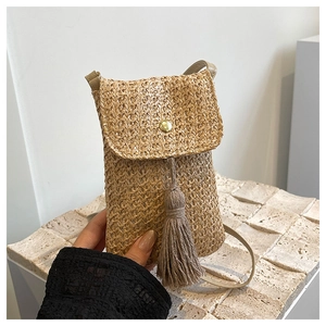 Detail of straw woven phone bag featuring a golden buckle and elegant long tassel decor