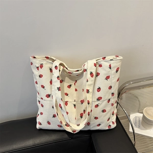 Minimalist white corduroy tote bag with red strawberry pattern in a cozy home setting