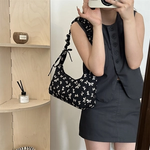 Minimalist black floral shoulder bag with white bow patterns and ruffled strap design