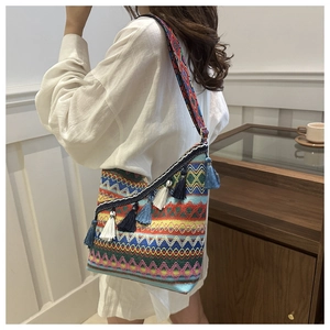Detail van de Boho gebreide tas met kleurrijke patronen en lange kwastjes aan de zijkant