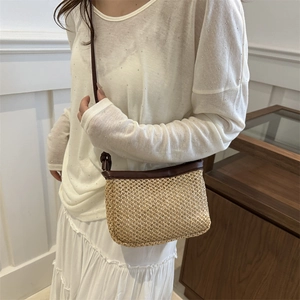 Beige woven straw crossbody bag with dark brown leather trim shown on a model