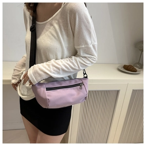 Close-up of a light purple nylon crescent bag with adjustable black shoulder strap on a model