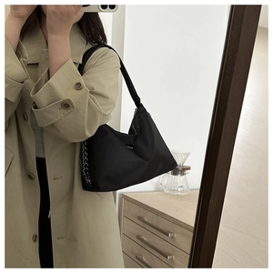 Detail of black nylon tote bag featuring a stylish thick silver chain on the side strap