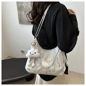 Détail de la broderie sur un sac hobo blanc avec motifs de vagues et breloque nuage