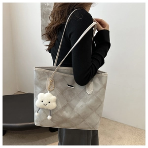 Detail of grey quilted tote bag featuring a white cloud plush charm and long shoulder straps