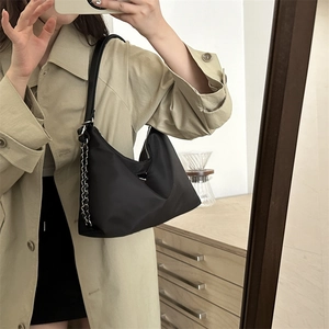 Minimalist black nylon shoulder bag with silver chain strap shown on a model
