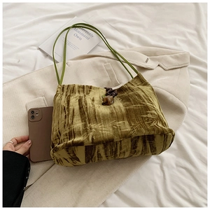 Macro view of velvet tote bag featuring olive green texture and wooden button closure