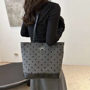 Spacious heart print tote bag with black bow embroidery and leather base on a model
