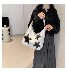 Close-up of a white canvas tote bag featuring black star patterns and sleek shoulder strap