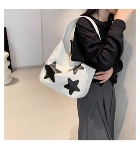 Detailed shot of large capacity white tote bag with black star pattern and wide shoulder strap