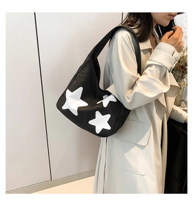 Detail of black shoulder tote bag featuring bold white star prints for daily casual use