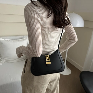 Classic black leather baguette shoulder bag with a gold geometric clasp shown on a model