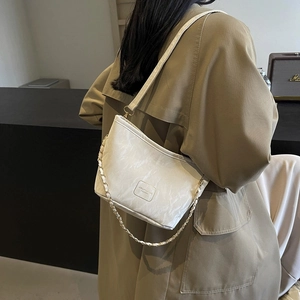 Sac seau blanc motif marbre avec chaîne dorée porté par un mannequin à l'épaule