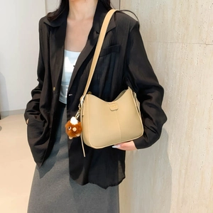 Fashionable beige PU shoulder bag with bear pendant shown on model in stylish outfit