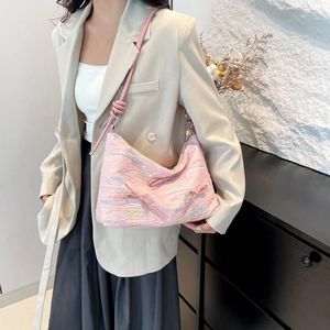 Pink quilted shoulder bag with colorful embroidery and bow detail on beige blazer