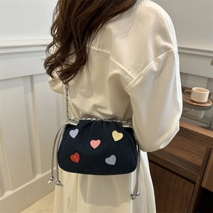 Blue denim bucket bag with colorful heart patches and silver chain strap worn by model