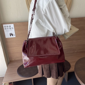 Glossy burgundy leather underarm bag with silver chain strap shown on model