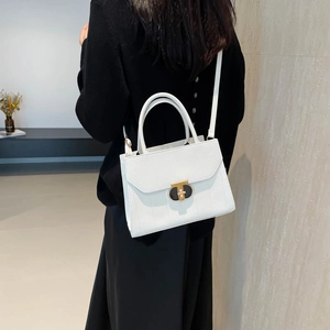 Petit sac carré blanc en cuir grainé avec fermoir doré porté à l'épaule par un mannequin