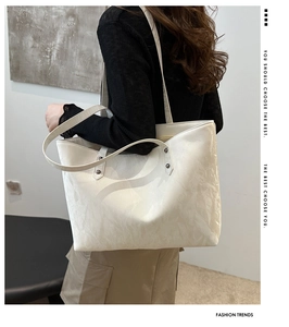 Detail of minimalist off-white tote bag with marble texture and silver rivets on shoulder strap