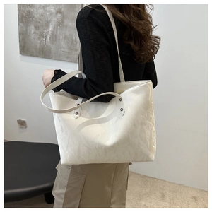 Detailed view of the white tote bag featuring unique pleated texture and metal rivet accents
