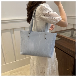 Detail of light blue pleated PU leather tote bag with stylish rivet strap attachments