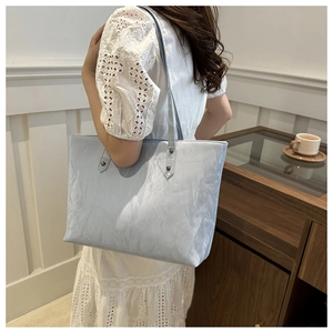 Gros plan du sac cabas plissé bleu clair avec fines brides sur mannequin en blanc