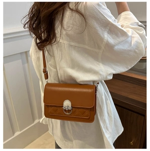 Brown quilted crossbody bag with silver twist lock shown on a model in a modern interior