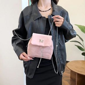 Pink velvet crossbody bag with silver butterfly buckle and chain strap shown on model