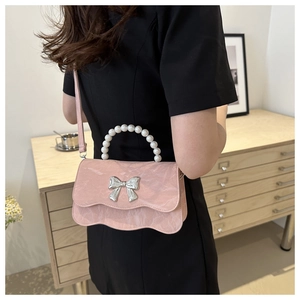 Detail of pink stone-textured handbag with pearl handle and silver bow on wave-edge flap