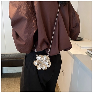 Dettaglio di una mini borsa a fiore in metallo argento con finitura a specchio e catena