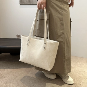 Sac fourre-tout beige minimaliste avec détails rivetés présenté dans un cadre décontracté
