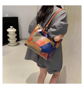 Side view of a geometric patchwork leather tote bag with brown straps on model shoulder