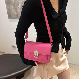 Petit sac à bandoulière matelassé rose avec boucle argentée porté par un mannequin