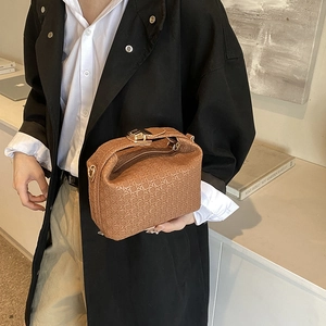 Brown woven texture handbag with gold buckle shown in a modern urban style on a model