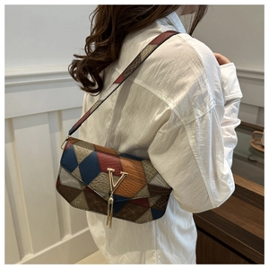 Detail view of geometric patchwork shoulder bag featuring metal V logo and tassel charm.