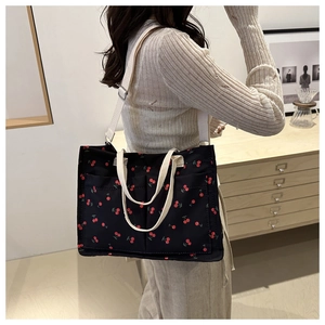 Dettaglio della borsa tote in nylon floreale con stampa ciliegia e tracolla regolabile
