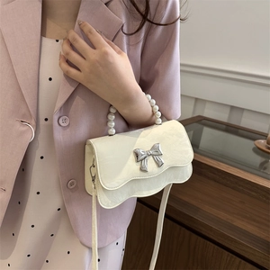 Elegant off-white pearl handle bag with silver metal bow and wavy edge design