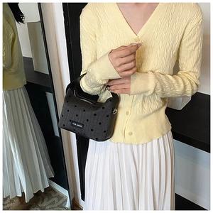 Dark grey polka dot handbag paired with a yellow cardigan and white pleated skirt