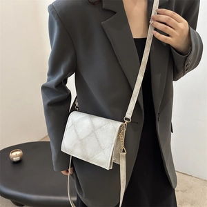 Borsa a tracolla minimalista con motivo a rombi e dettagli dorati su blazer grigio