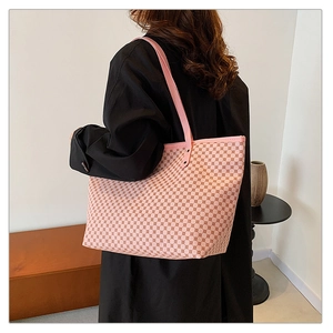 Detail of pink geometric pattern tote bag with slender leather straps on model shoulder