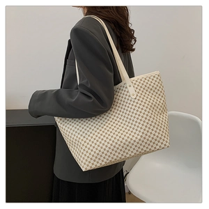 Side view of a large check pattern tote bag with cream leather straps and gold rivets