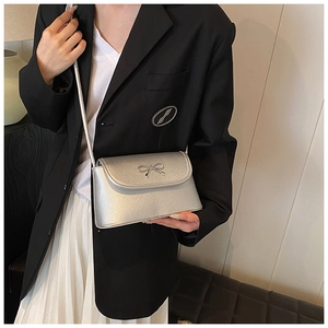 Silver metallic crossbody underarm bag detail showcasing elegant bow hardware accent.