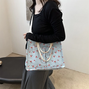 Floral nylon tote bag in light blue with red cherry print and adjustable shoulder strap