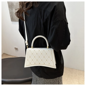 White hourglass-shaped crossbody bag with quilted leather and golden stud details