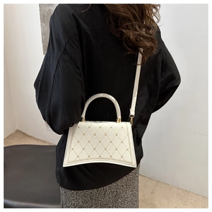 Model view of white quilted crossbody bag with gold studs and curved bottom detail