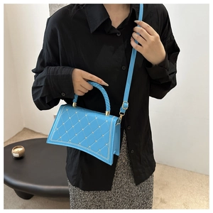 Detail of light blue crossbody bag with gold heart studs and quilted diamond pattern