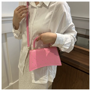 Detail of pink quilted handbag showing gold heart studs and woven handle texture